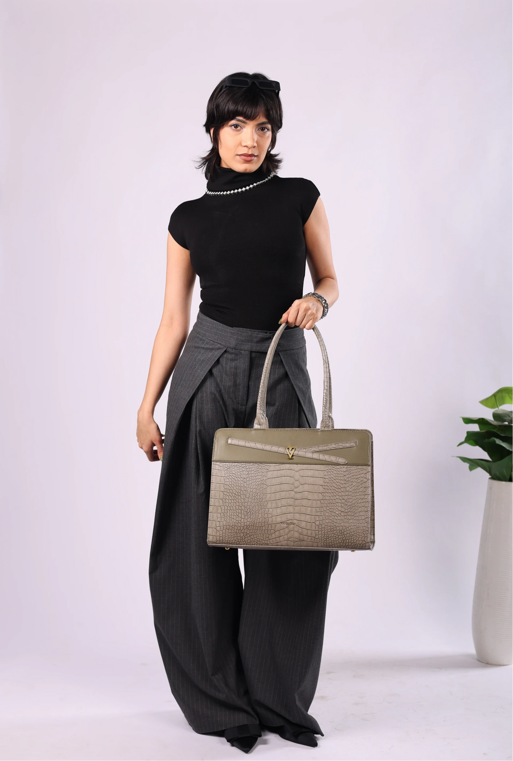 Woman holding a gray handbag against a white background